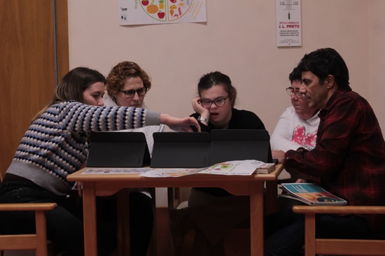 cuatro personas trabajan en grupo en una mesa con ordenador 
