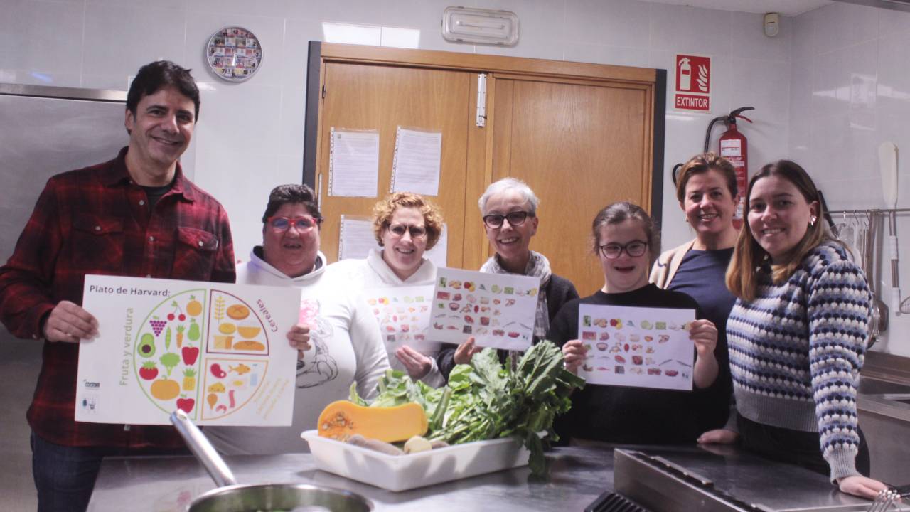 grupo de personas en una cocina con alimentos y carteles sobre la dieta